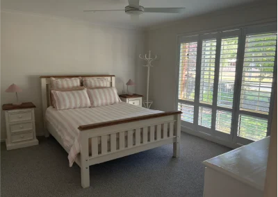 landscape shot of master room with shutters and pink stripe bedding